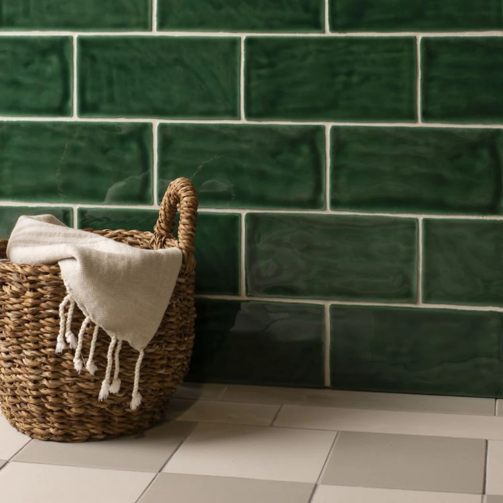 Tourmaline Brick Tile splashback detail – glossy emerald-green tiles with natural shading, paired with light grout for contrast and a warm, textured basket in the foreground.