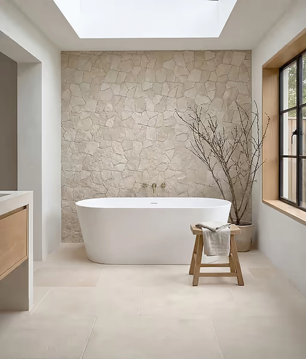 Sierra porcelain wall tiles with a natural stone-look pattern on a bathroom wall, paired with a freestanding bath and soft natural light.