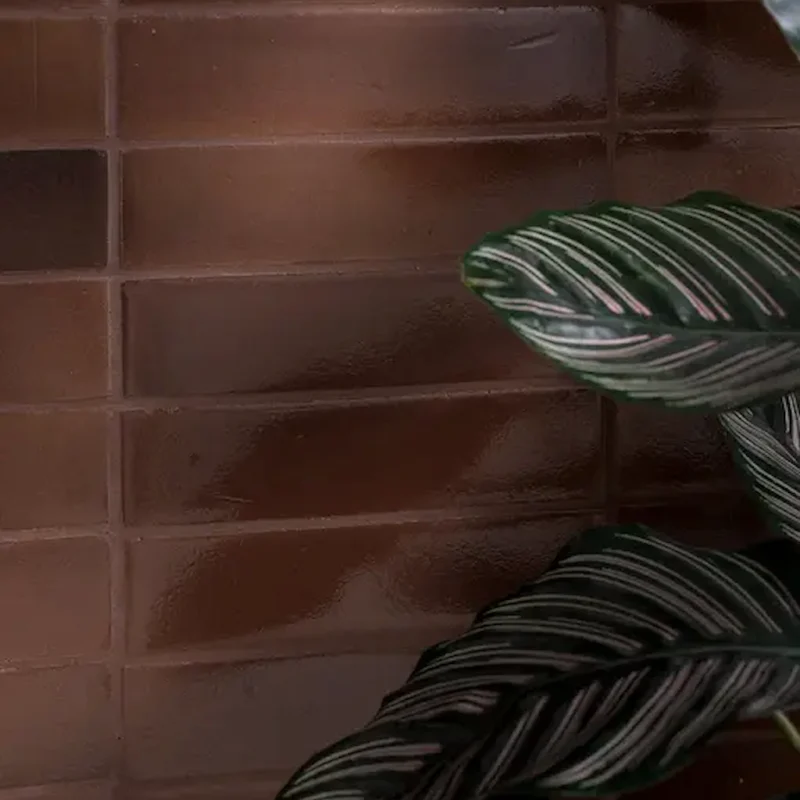 Close-up of Stone Glaze Cola 5x20cm ceramic wall tiles with a glossy deep brown finish