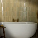 Stone Glaze Chambray 5x20cm ceramic tiles with soft beige and cream tones, arranged vertically behind a freestanding bath