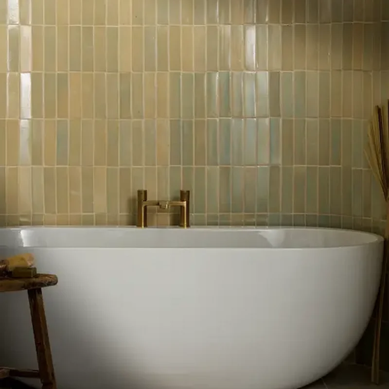 Stone Glaze Chambray 5x20cm ceramic tiles with soft beige and cream tones, arranged vertically behind a freestanding bath