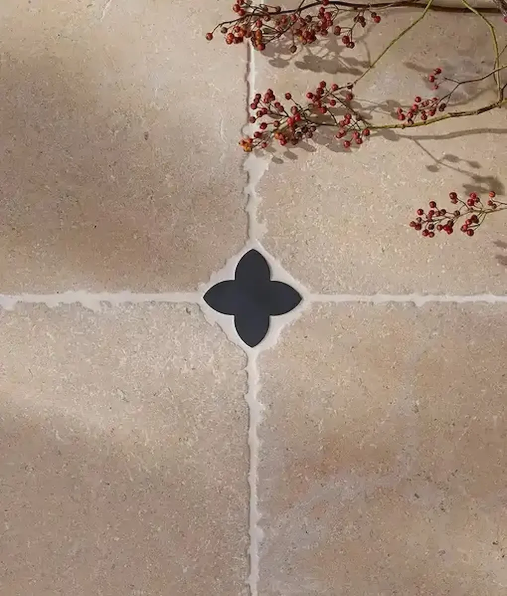 Beige stone floor tiles, featuring the small Clover Cabochon Nero at the grout intersection for a decorative accent.