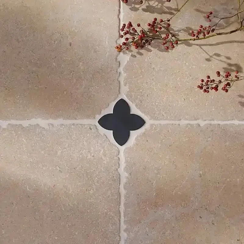 Beige stone floor tiles, featuring the small Clover Cabochon Nero at the grout intersection for a decorative accent.