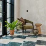 Versailles Cream tiles laid in a classic chequerboard pattern with green marble tiles, styled with an olive chair and indoor plant.
