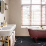 Versailles Marble Noir 45.7x45.7cm tiles in a bathroom, showing the deep black marble with white veining beneath a freestanding bath.