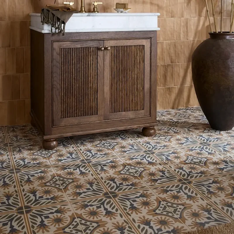 Indirah Porcelain Cotto patterned floor tiles in a bathroom setting, showing a warm terracotta, blue and cream geometric designs paired with a wooden vanity unit.