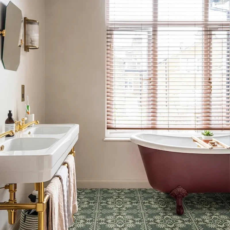 Indirah Porcelain Emerald patterned floor tiles in a bathroom, showing a green geometric design paired with a freestanding bath and brass fittings.