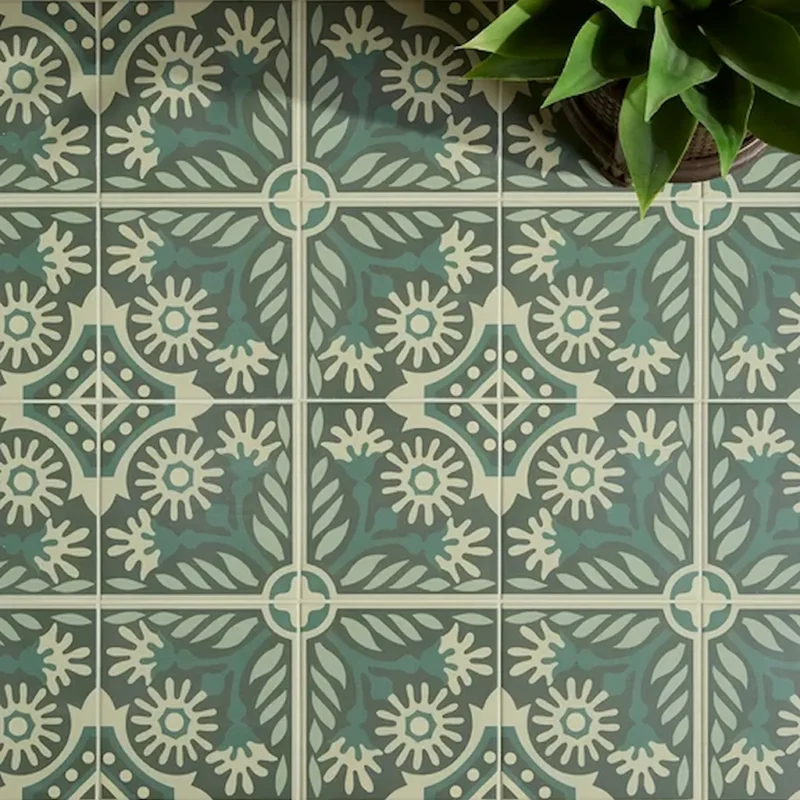 Close-up of Indirah Porcelain Emerald tiles showing a repeating geometric pattern in muted green and cream tones.