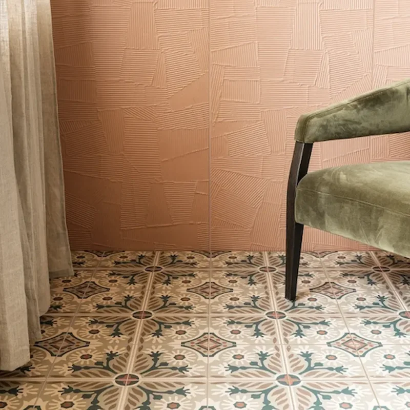Indirah Porcelain Mocha patterned floor tiles with soft beige, taupe and muted blue tones, paired with a textured terracotta wall and green velvet chair.