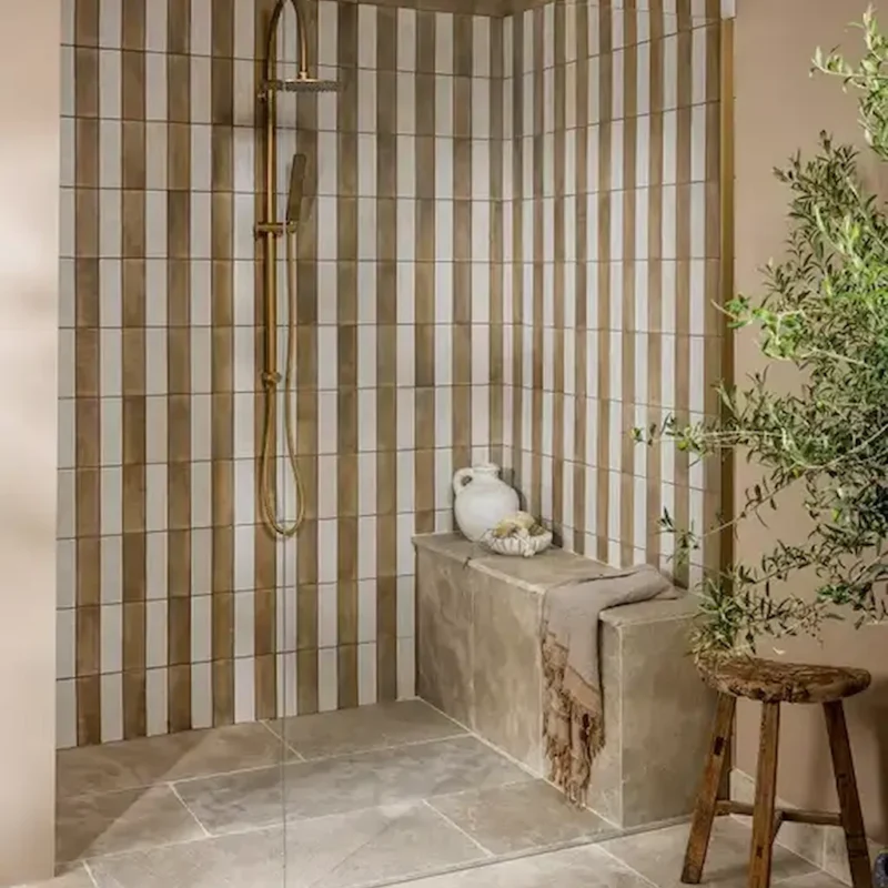 Oasis Veloute Ceramic Tan and white tiles installed vertically in a shower area, creating a soft striped effect with warm neutral tones.