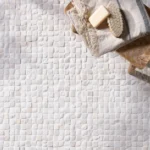 Enso Cobble Mosaic Cube Chalk 30x30cm tiles, small rounded limestone mosaic in soft chalk tones, natural textured bathroom surface with towel and soap