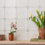 Spring May Delft style tiles installed on a wall showing green leaf corner pattern with tulips and small flowers on a wooden shelf