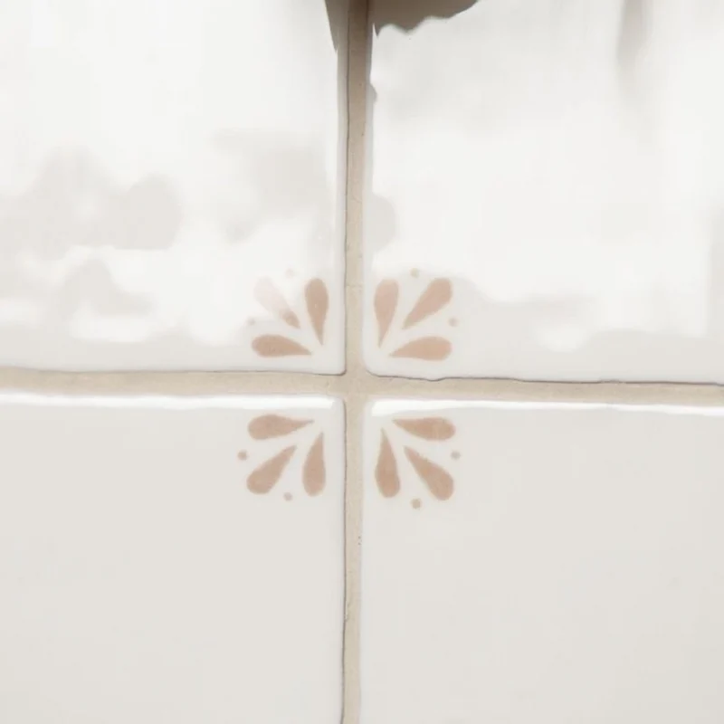 Close-up of Country Delft Cornelia Taupe tiles showing hand-painted taupe corner pattern and grout lines