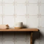 Country Delft Ada Taupe wall tiles with floral corner detailing in a warm taupe tone above a wooden shelf.