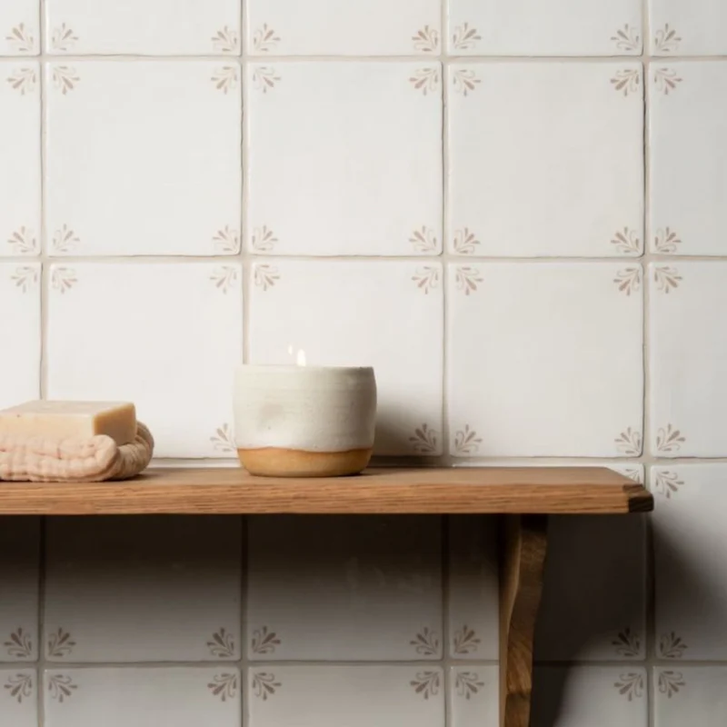 Country Delft Ada Taupe wall tiles with floral corner detailing in a warm taupe tone above a wooden shelf.