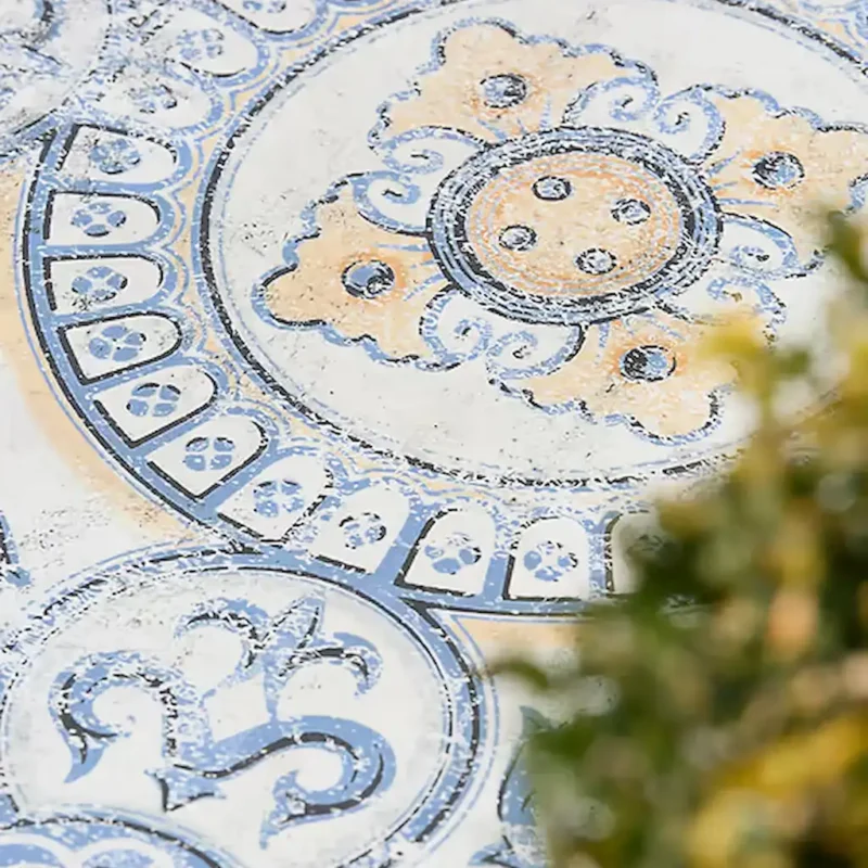 Outdoor setting showing Tapestry Porcelain Paving textured geometric tiles with vintage-inspired blue, cream, and grey circular patterns.