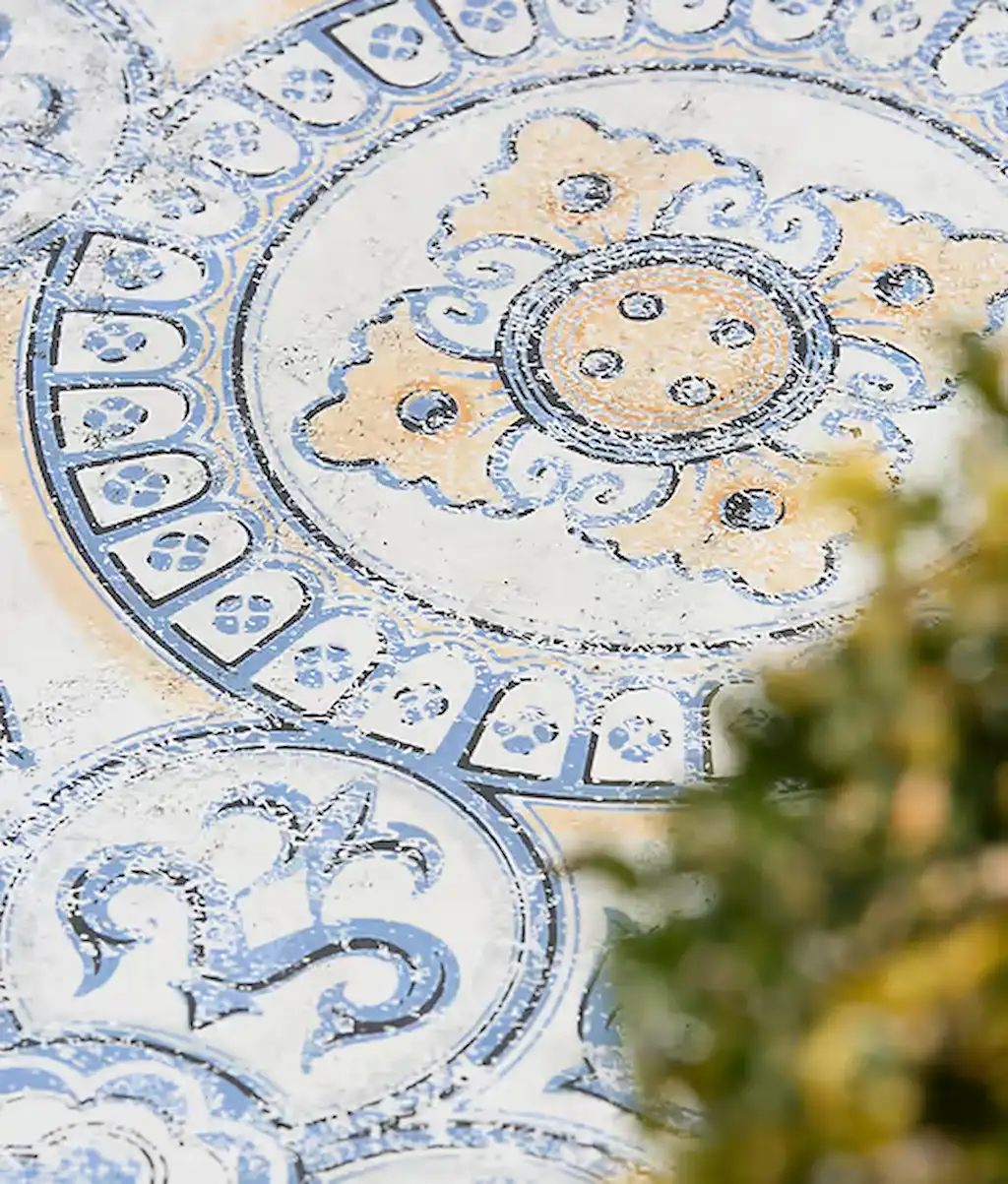 Outdoor setting showing Tapestry Porcelain Paving textured geometric tiles with vintage-inspired blue, cream, and grey circular patterns.